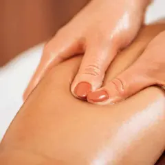 Mani esperte eseguono un massaggio per snellire le ginocchia, con olio che dona lucentezza alla pelle.