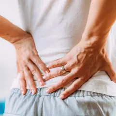 Mani che premono sulla schiena dolente, cercando sollievo nei punti shiatsu per sciatica.