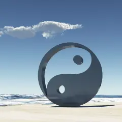 Simbolo Yin e Yang sulla spiaggia, con onde e cielo azzurro. Rappresenta l'equilibrio universale, il yin e yang significato esoterico.