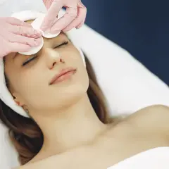 Estetista esegue un delicato massaggio viso con dischetti di cotone, per un trattamento di bellezza rilassante.