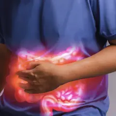 Persona che si tiene la pancia, con un'illustrazione luminosa dell'intestino. Un aiuto per l'automassaggio colon irritabile.