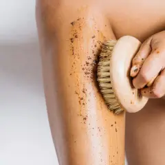 Mano che massaggia la gamba con uno scrub, dimostrando che i fanghi per cellulite funzionano per una pelle liscia.