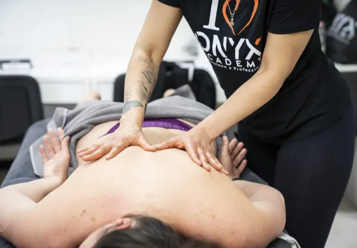 Hands massaging a person's back on a massage table.