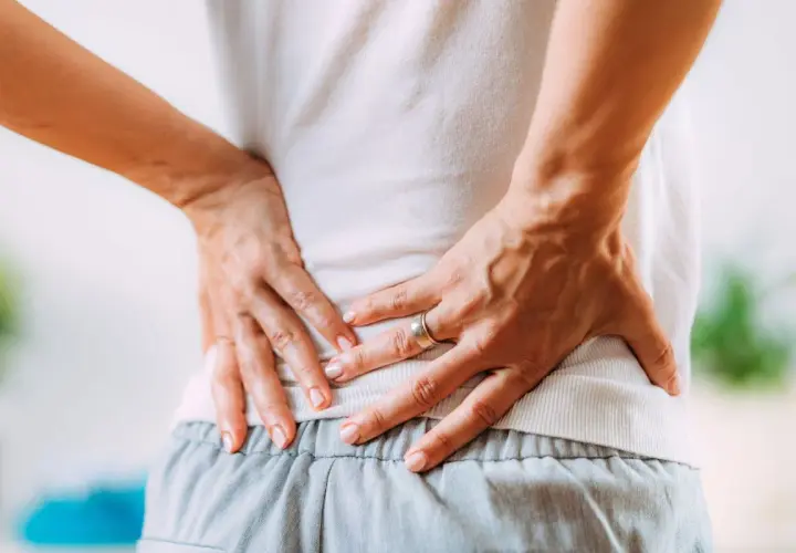 Mani che premono sulla schiena dolente, cercando sollievo nei punti shiatsu per sciatica.