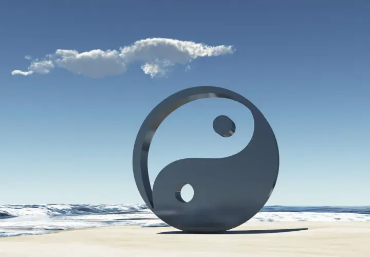 Simbolo Yin e Yang sulla spiaggia, con onde e cielo azzurro. Rappresenta l'equilibrio universale, il yin e yang significato esoterico.