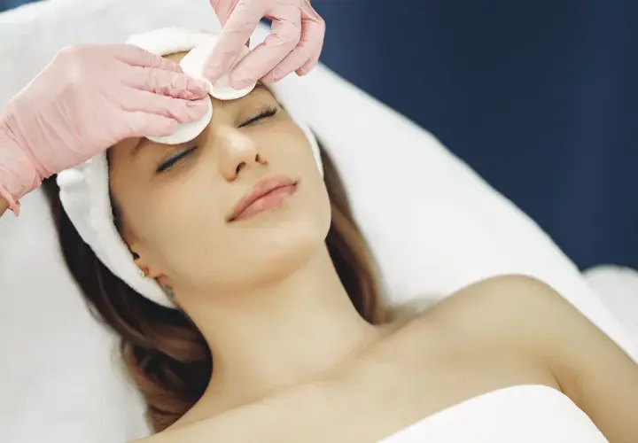 Estetista esegue un delicato massaggio viso con dischetti di cotone, per un trattamento di bellezza rilassante.