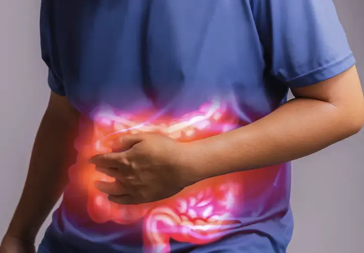 Persona che si tiene la pancia, con un'illustrazione luminosa dell'intestino. Un aiuto per l'automassaggio colon irritabile.