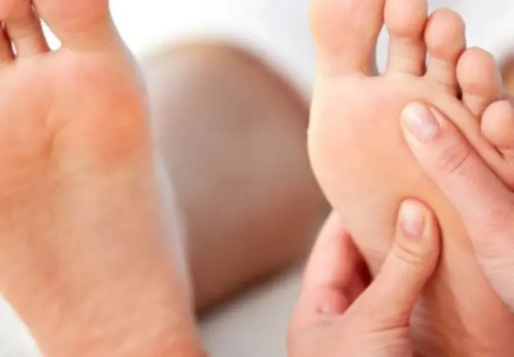 Close-up of hands massaging the sole of a foot.