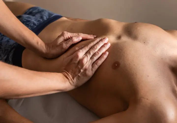 Mani esperte eseguono un rilassante massaggio addome uomo, sciogliendo tensioni e promuovendo il benessere.