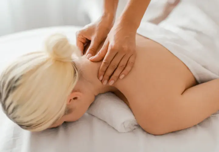 Hands massaging a woman's neck and shoulders.