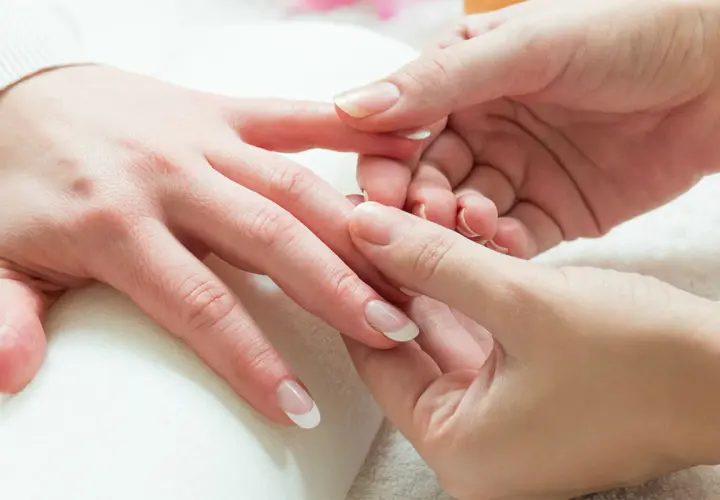 Mani curate e rilassate durante un delicato massaggio alle mani. Unghie perfette con french manicure.
