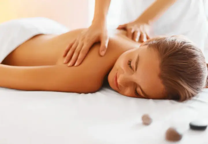 Woman receiving a relaxing back massage with hands on her shoulders and upper back.