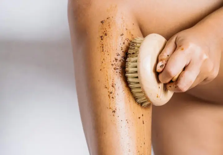 Mano che massaggia la gamba con uno scrub, dimostrando che i fanghi per cellulite funzionano per una pelle liscia.