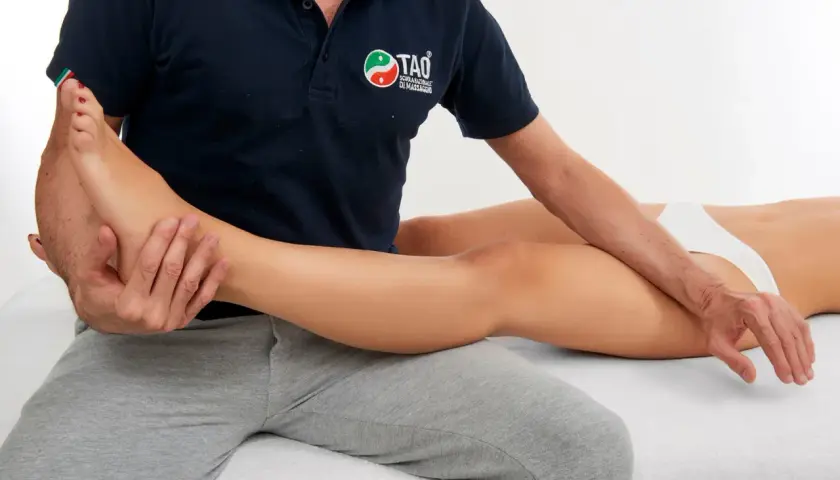 Un terapista esegue un massaggio thai oil alla gamba di una donna, concentrandosi sul piede e sulla caviglia per un rilassamento profondo.
