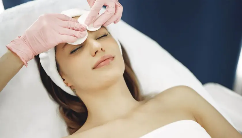 Estetista esegue un delicato massaggio viso con dischetti di cotone, per un trattamento di bellezza rilassante.