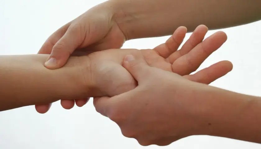 Mani che eseguono digitopressione per diarrea sul polso.