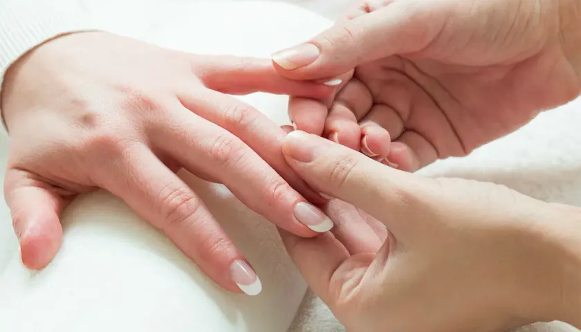 Mani curate e rilassate durante un delicato massaggio alle mani. Unghie perfette con french manicure.