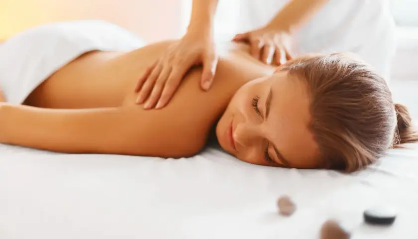 Woman receiving a relaxing back massage with hands on her shoulders and upper back.