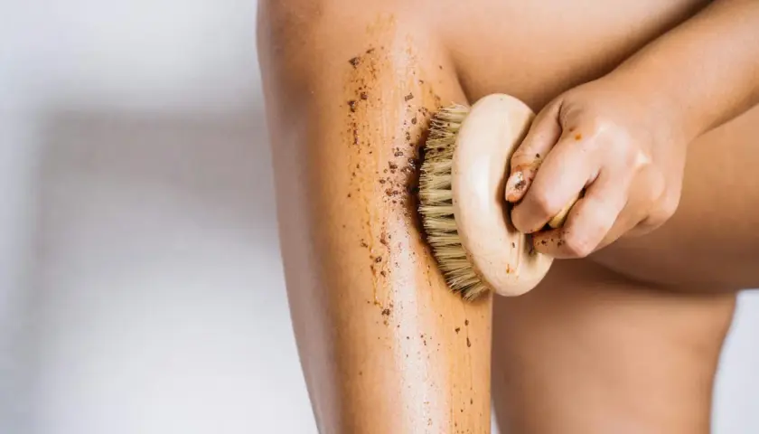 Mano che massaggia la gamba con uno scrub, dimostrando che i fanghi per cellulite funzionano per una pelle liscia.