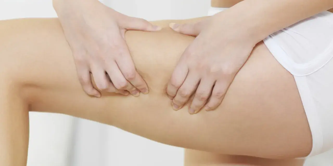 Mani che pizzicano la pelle per valutare il rilassamento cutaneo delle gambe.