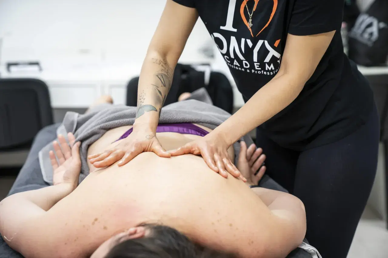 Hands massaging a person's back on a massage table.