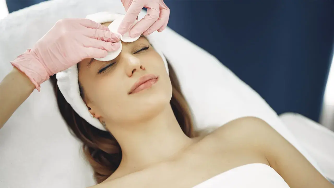 Estetista esegue un delicato massaggio viso con dischetti di cotone, per un trattamento di bellezza rilassante.