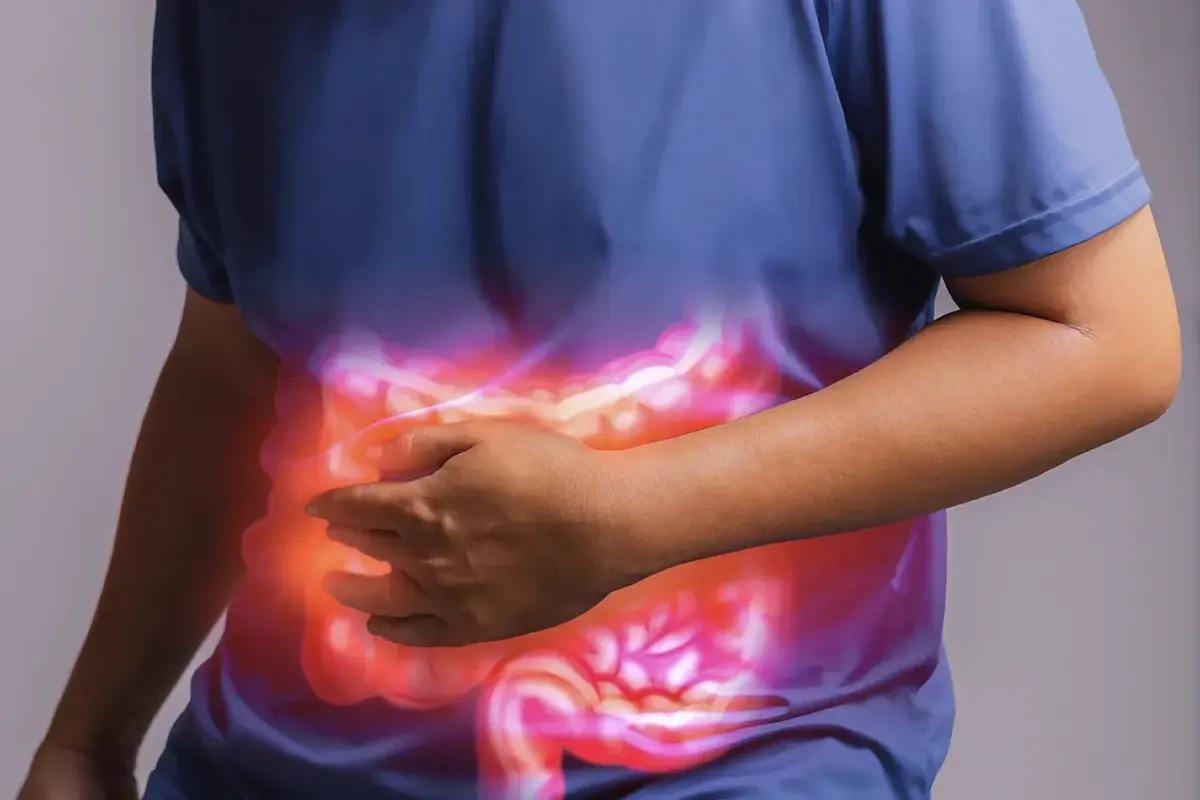 Persona che si tiene la pancia, con un'illustrazione luminosa dell'intestino. Un aiuto per l'automassaggio colon irritabile.