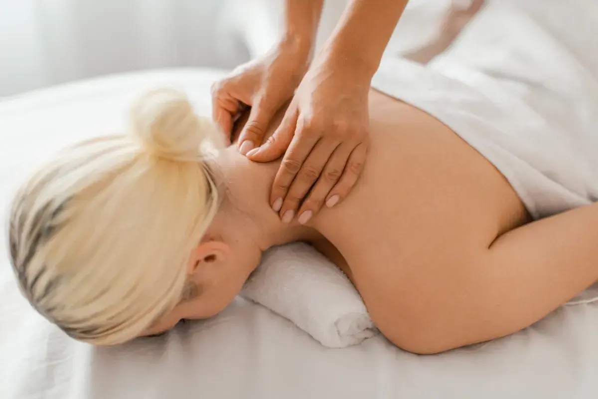 Hands massaging a woman's neck and shoulders.