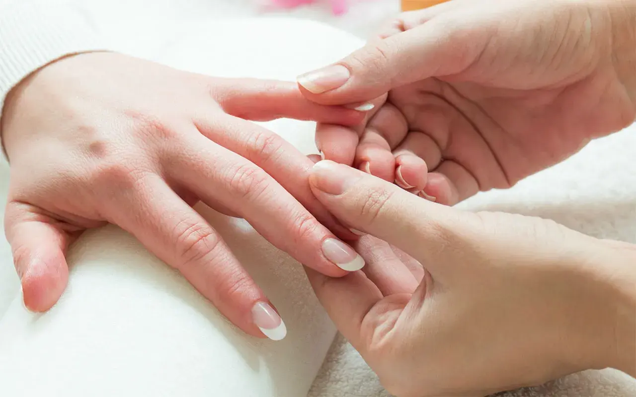 Mani curate e rilassate durante un delicato massaggio alle mani. Unghie perfette con french manicure.