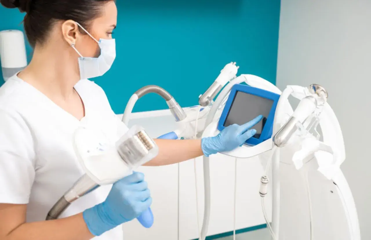 Operatrice con guanti blu e mascherina prepara un macchinario per il massaggio endodermico, toccando lo schermo.