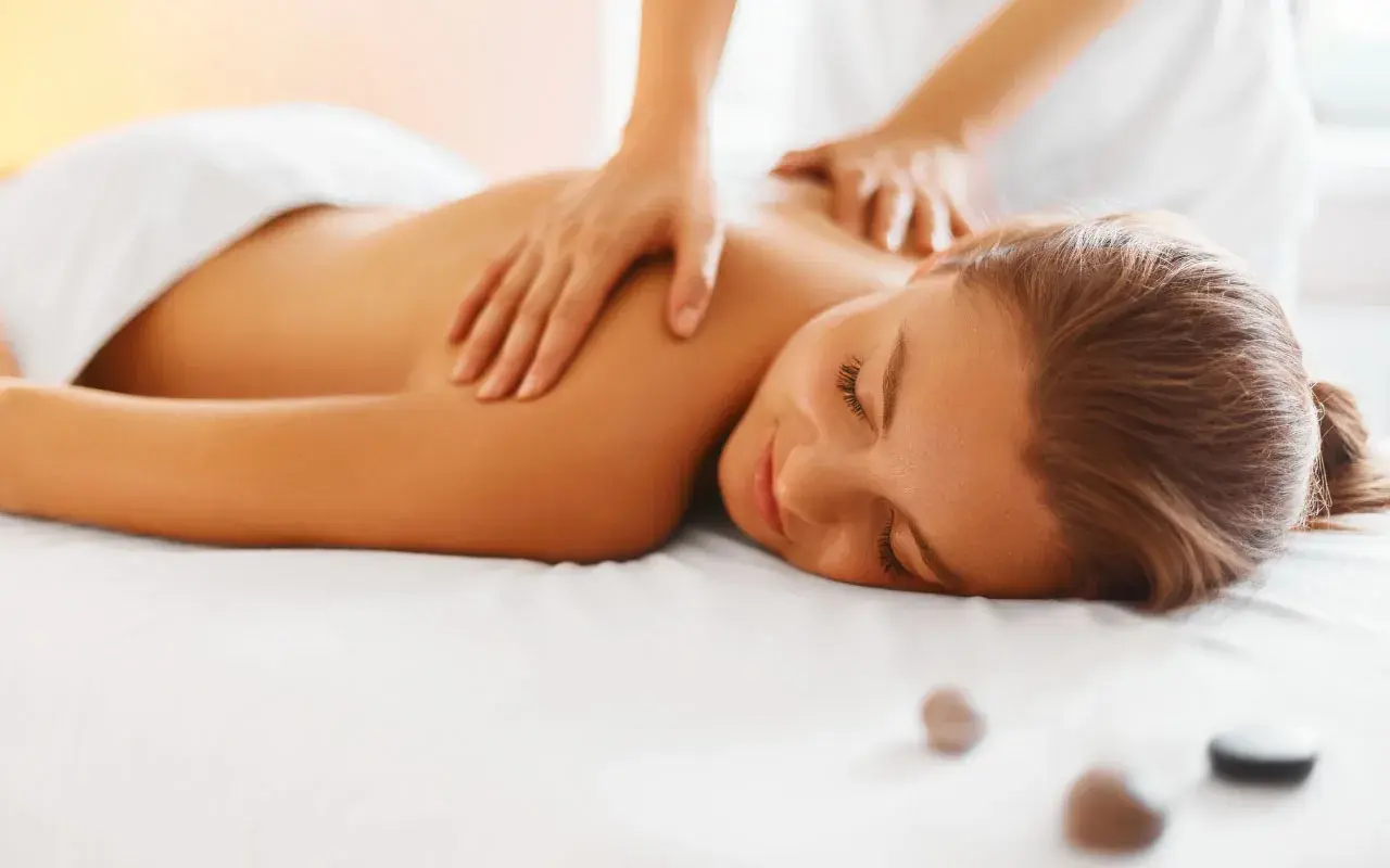 Woman receiving a relaxing back massage with hands on her shoulders and upper back.