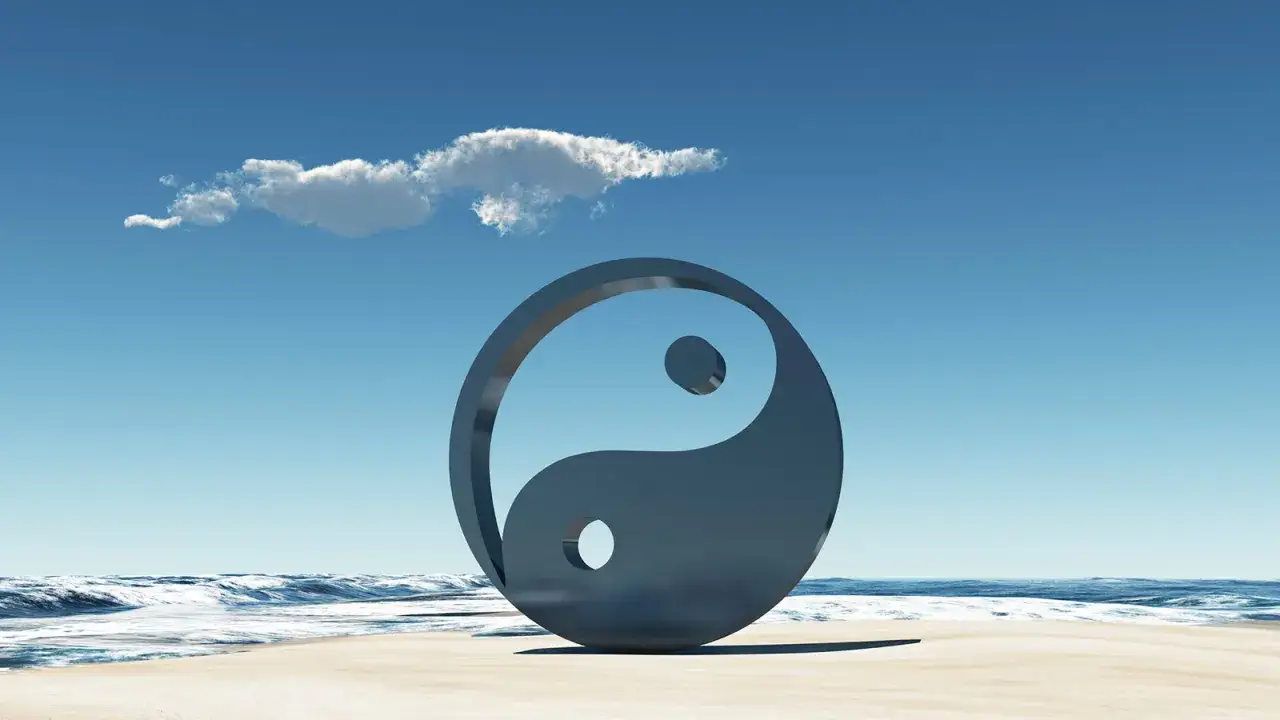 Simbolo Yin e Yang su una spiaggia, con onde e cielo azzurro. Rappresenta l'equilibrio universale e il yin e yang significato esoterico.